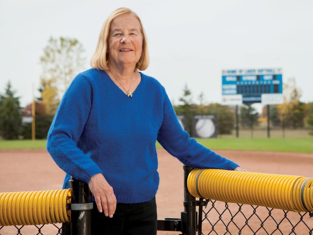 Joan Boand stands in front of a sports field.